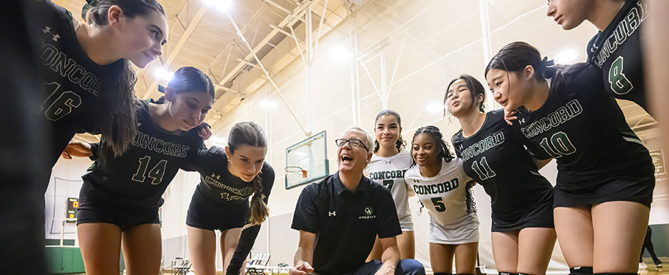 Volleyball team huddled with their coach